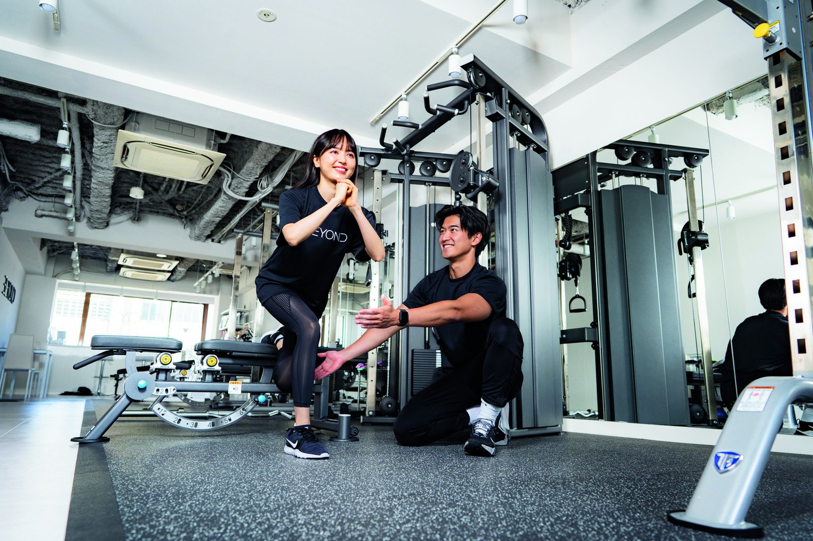 BEYONDの店内でトレーナーがお客様のトレーニングをサポートする様子